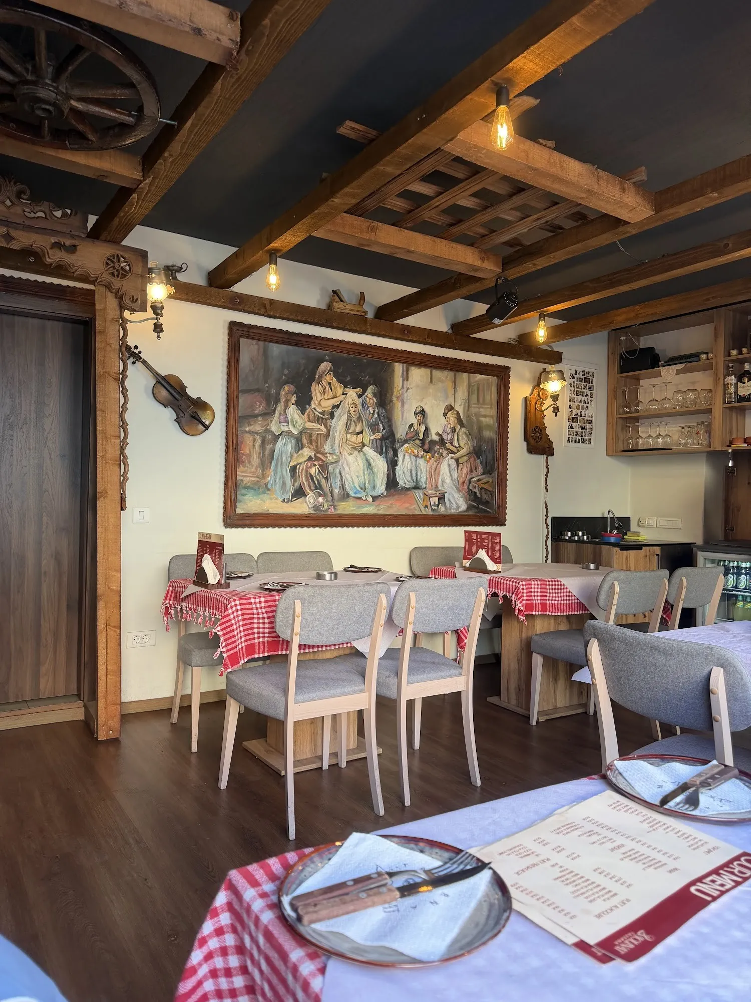 The taverna dining room with wooden ceiling beams, a painting and a violin on the wall