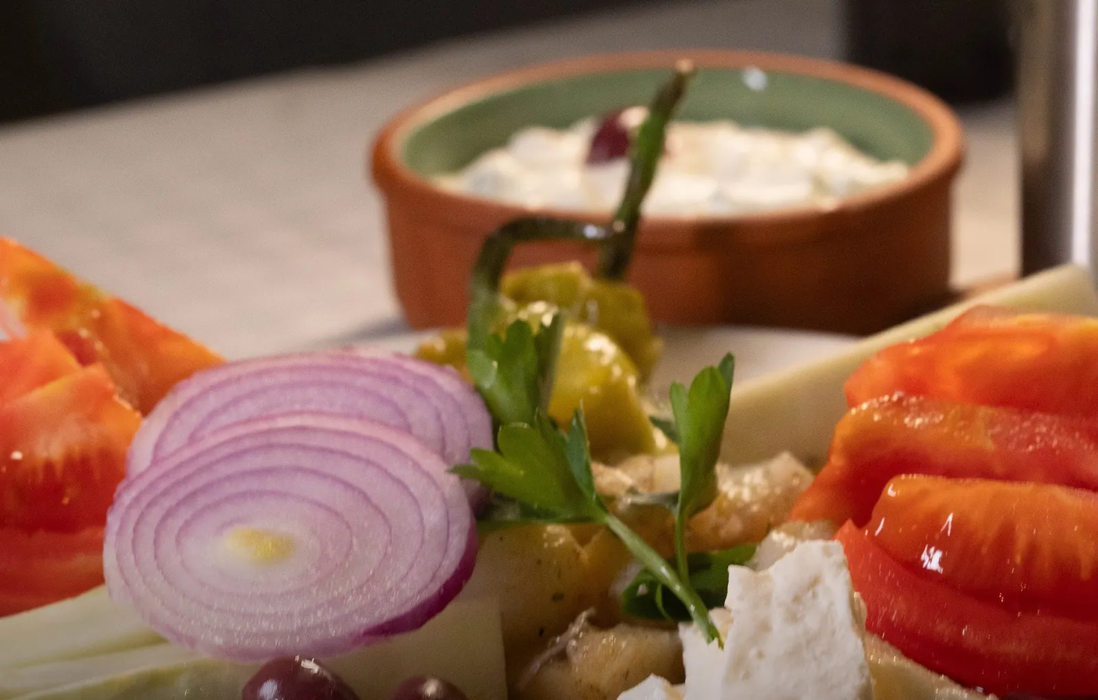 Meze plate of tomato, red onion, pepper, white cheese and olives with a bowl of tarator