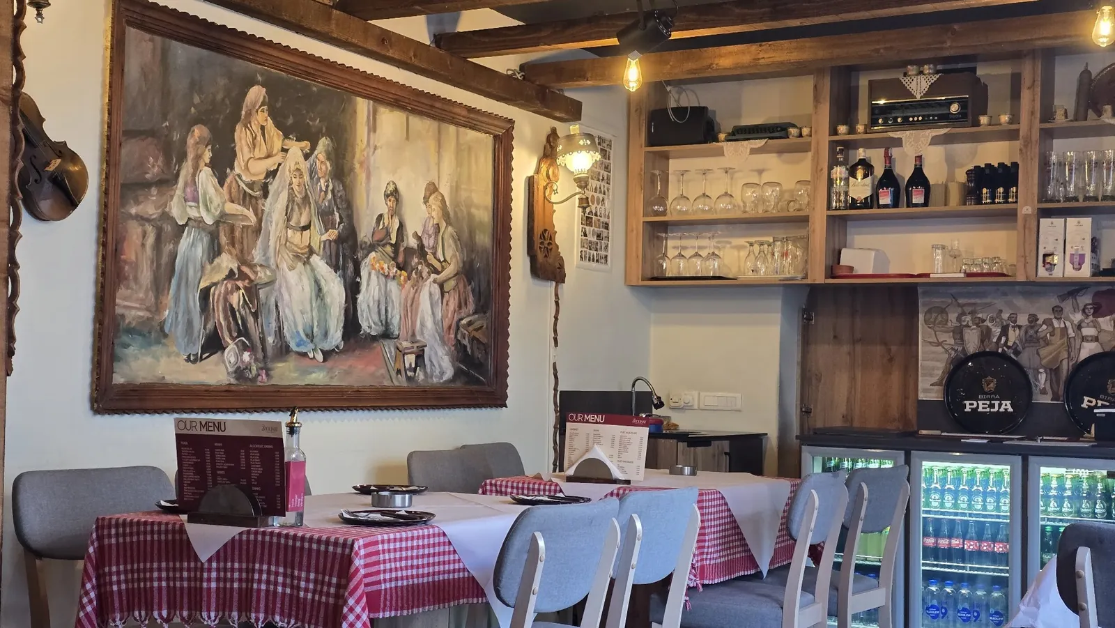 Dining room with red-checked tables under a painting of women in traditional dress