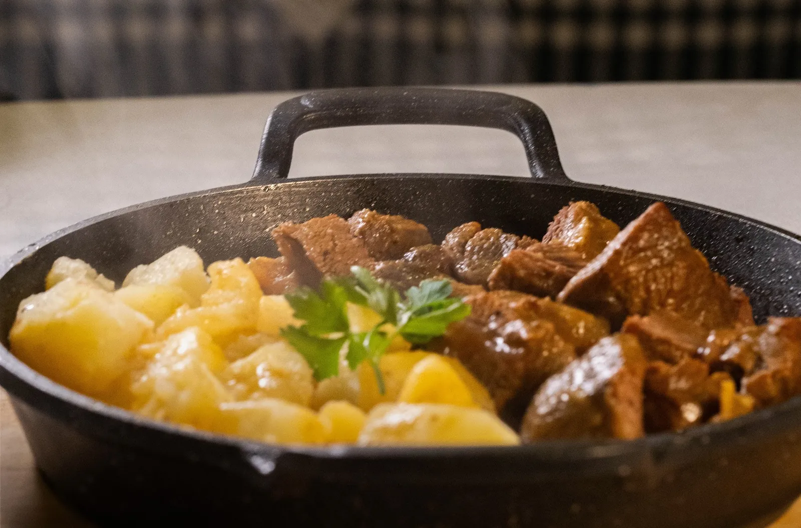 Cast-iron pan of stewed beef with potatoes and parsley
