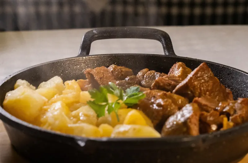 Cast-iron pan of stewed beef with potatoes and parsley