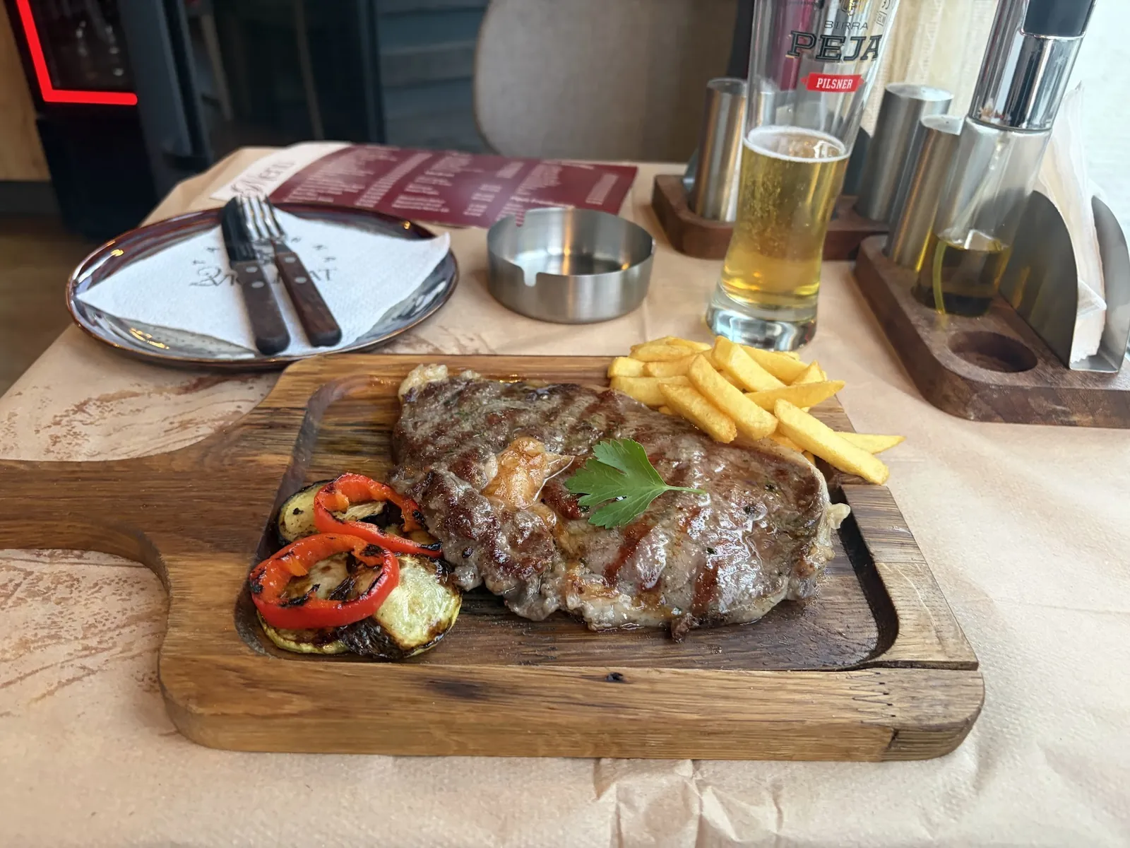 Grilled steak with French fries and grilled peppers on a wooden board