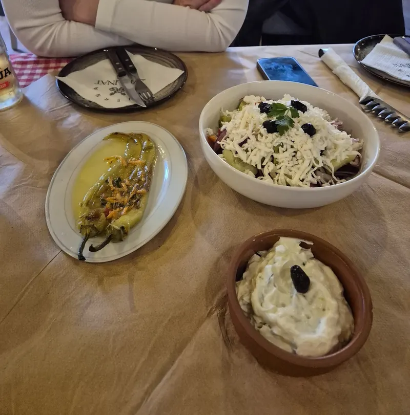 Table with shopska salad, a stuffed pepper and a bowl of tarator