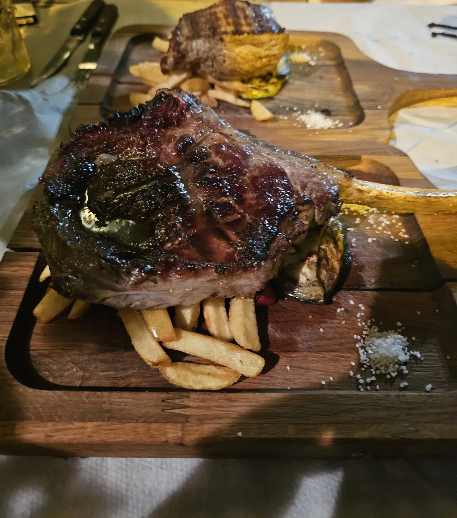 Tomahawk steak served over French fries on a wooden board
